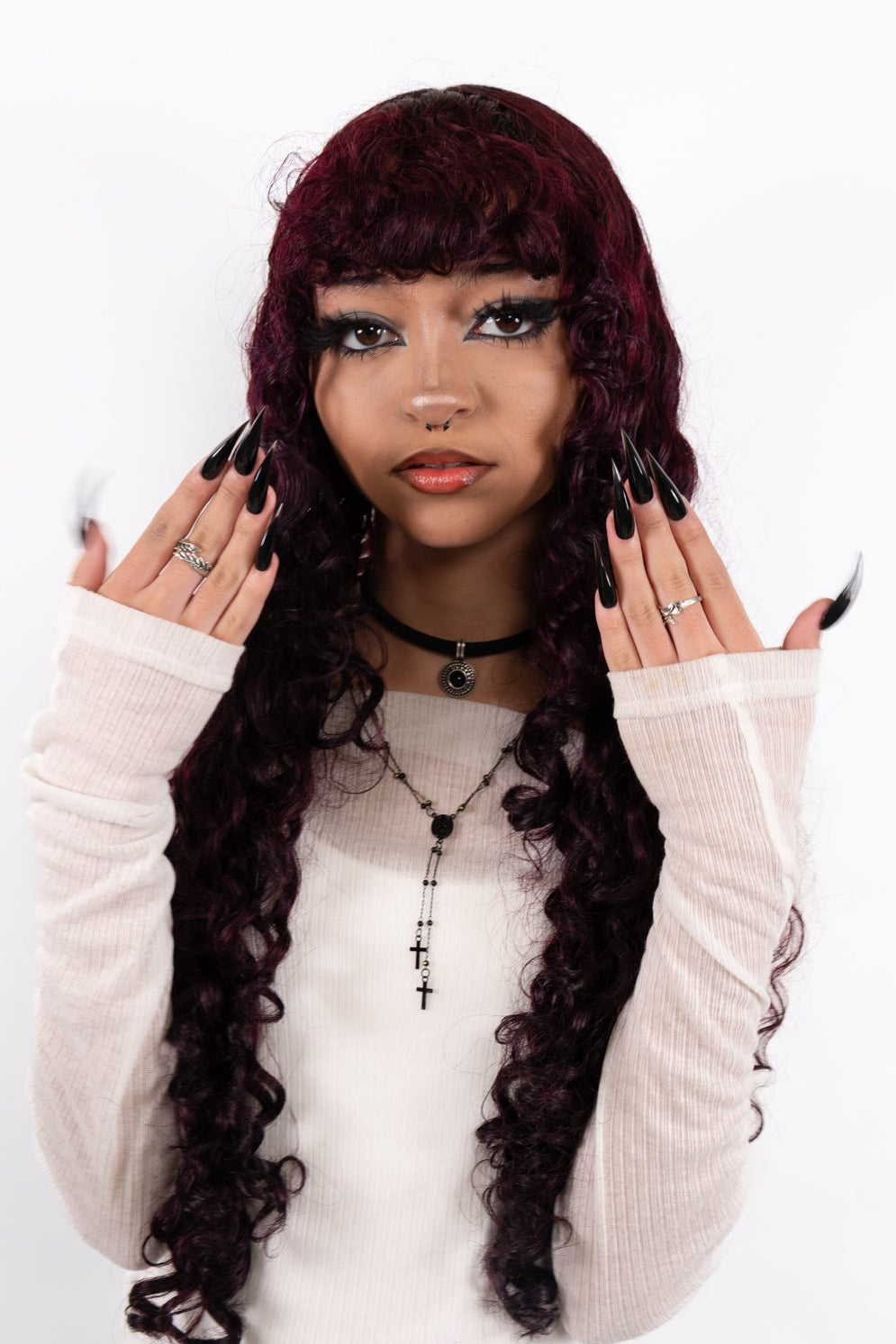 Woman with long, dark hair and white sweater against a white background